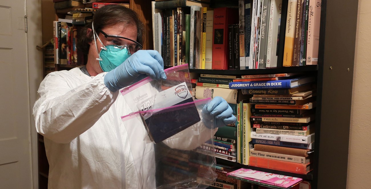 Man in PPE inserting item into Ziploc bag