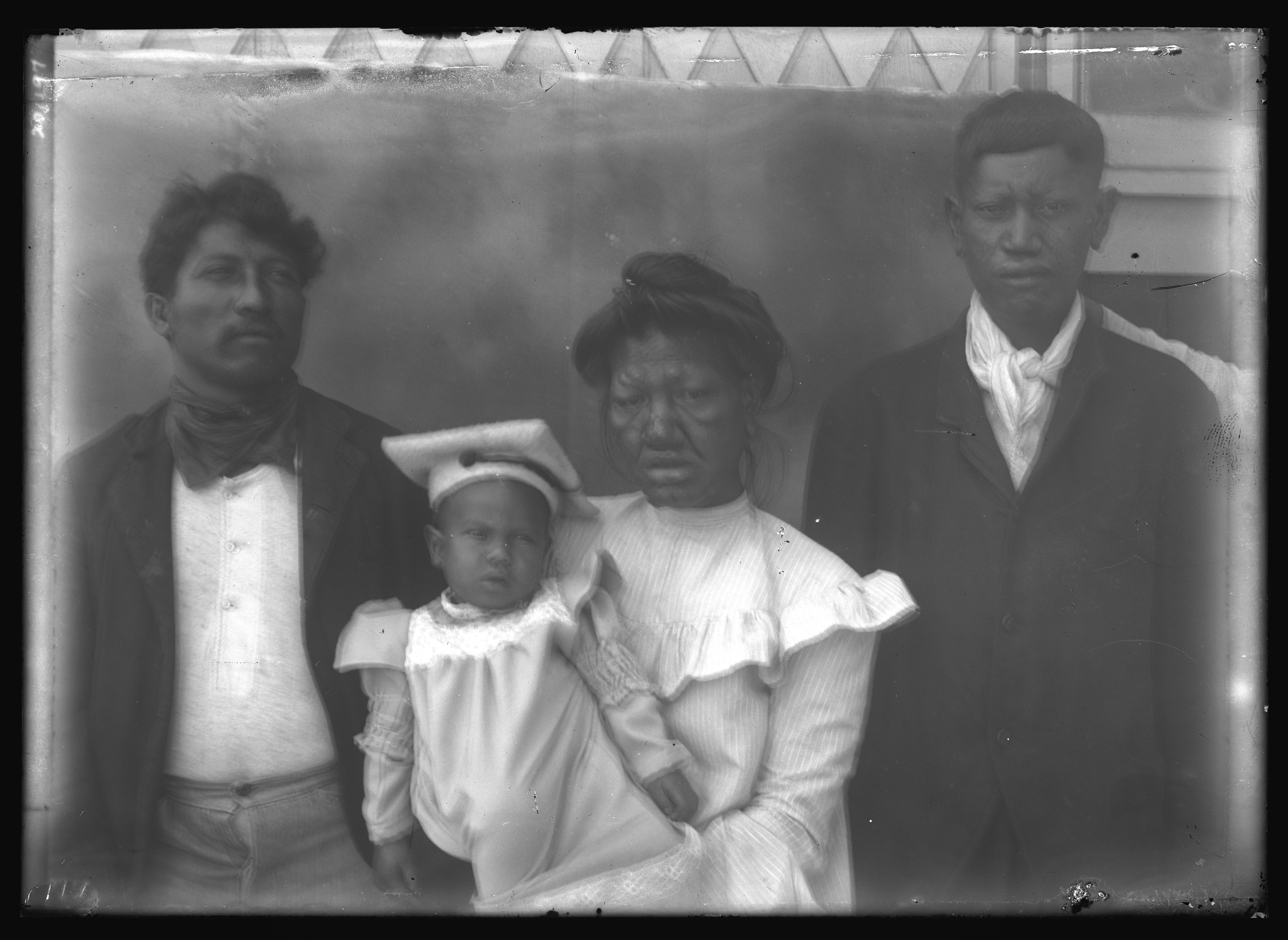 Portrait; black and white photo of two men on either side of a woman holding a child.