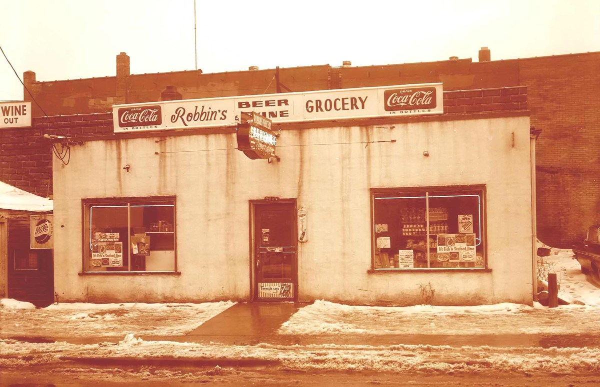 A sepia-toned photo of a small grocery store with a sign that reads Robbin's Grocery
