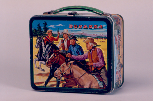 A metal lunch box emblazoned with an illustration of a scene from the television series Bonanza