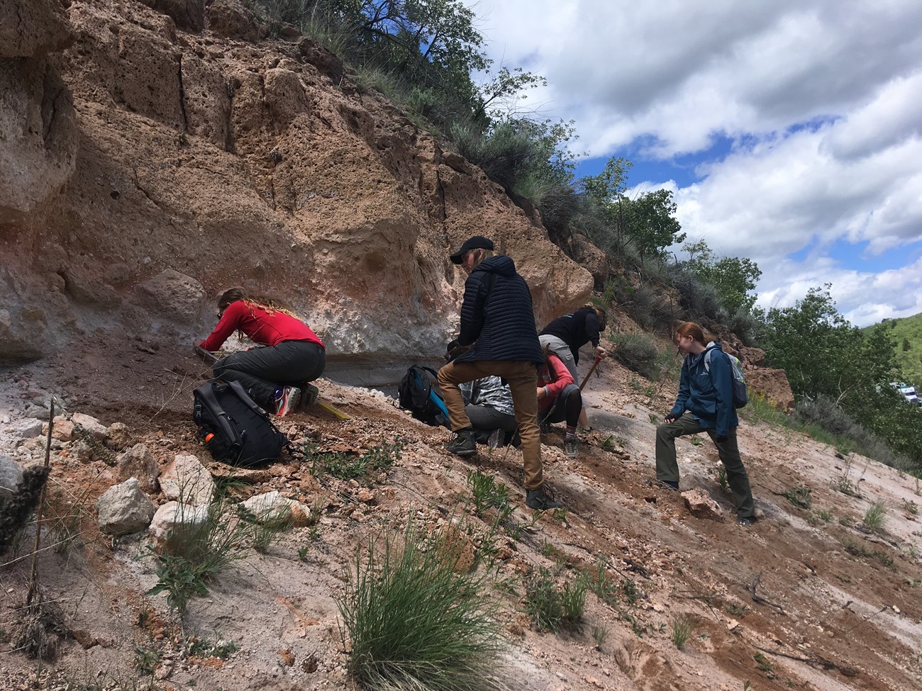 Photo of a small group of people examining a rock cliff.