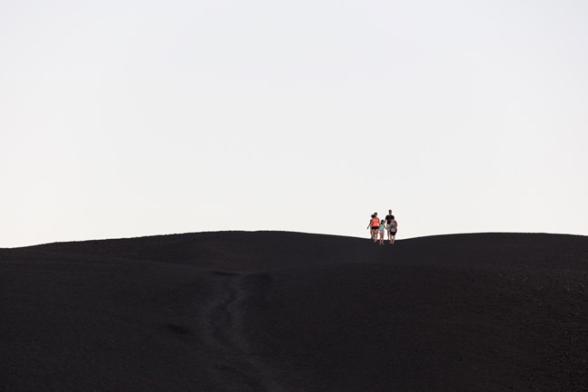 Hikers on Inferno Cone, a dark, barren cinder slope