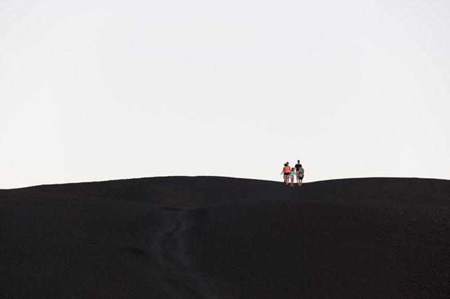 Inferno Cone Hikers on Inferno Cone, a dark, barren cinder slope