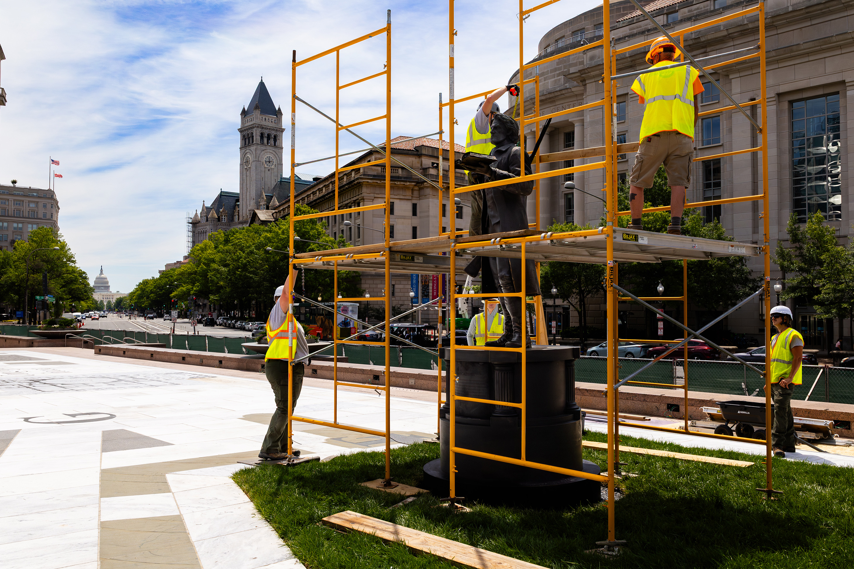 Dark bronze statue surrounded by scaffolding and workers in hard hats and hi-vis vests