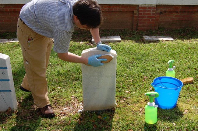 Jason Church demonstrates the top-down approach for cleaning headstones while in a cemetery.