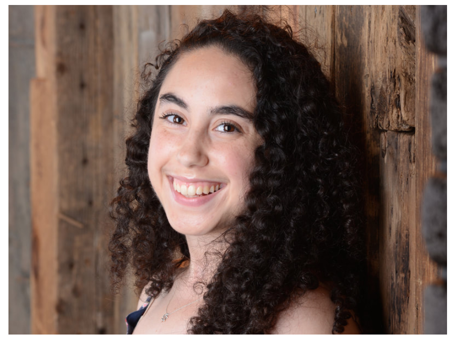 Smiling woman with dark curly hair.