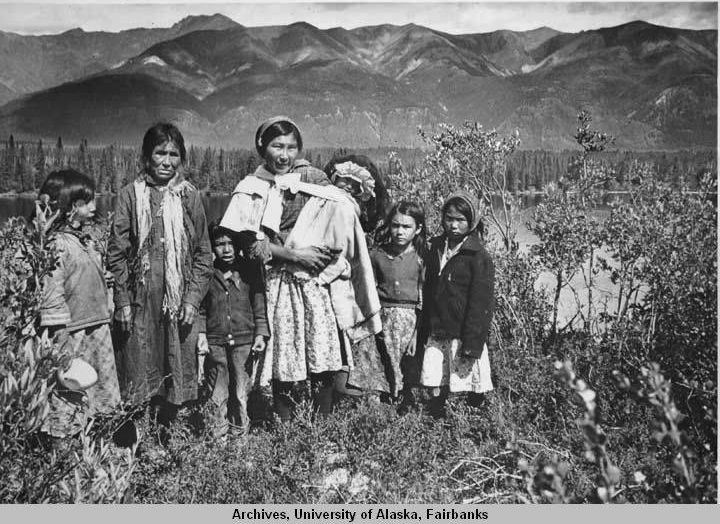 an alaska native woman surrounded by six children in an outdoor setting