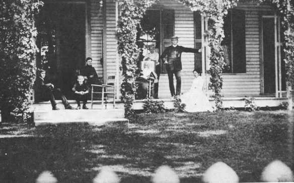 a group of people sitting in rocking chairs on a front porch of a home