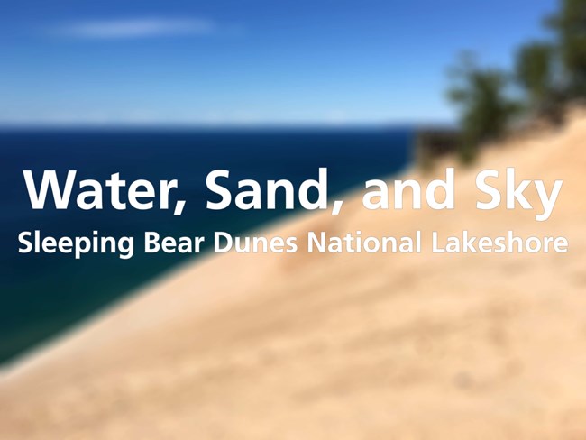 text: Water, Sand, and Sky Sleeping Bear Dunes National Lakeshore. Text over blurred image of sand, water, and sky