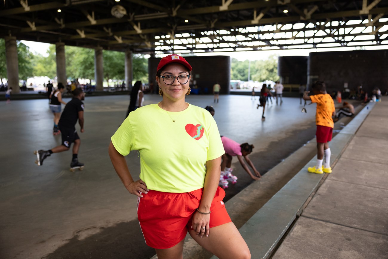Lydia Daniel smiles for a photo while wearing a light green Friends of Anacostia Park T-shirt Lydia Daniel smiles for a photo while wearing a light green Friends of Anacostia Park T-shirt on the steps of the rink at Anacostia Park Skating Pavilion in Washington, D.C., on June 28, 2025.