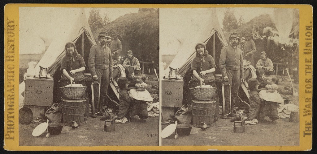 laundress A stereoscope image of a woman in an army camp holding a basket of laundry.