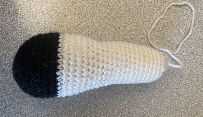 Mountain goat leg made out of white and black yarn.