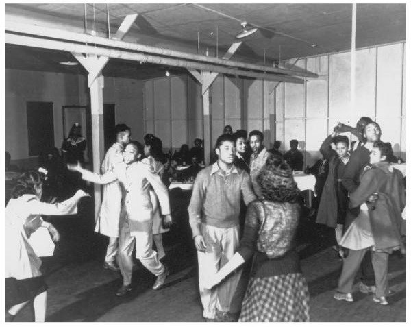 Teen dance at a recreation hall, Oak Ridge, TN. Photo by Ed Westcott, 1945. Courtesy US Department of Energy. A group of African American teenagers dance inside a building.
