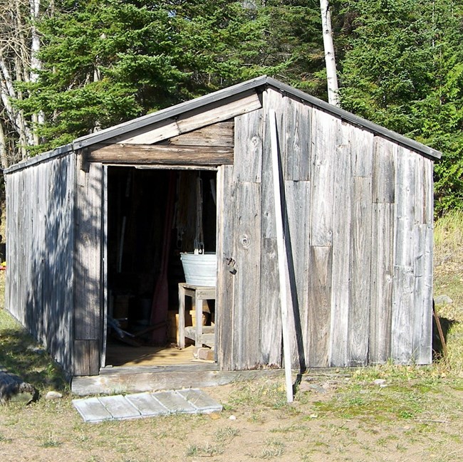 Wood shack with open sliding door, view of inside - washtub on a stand.