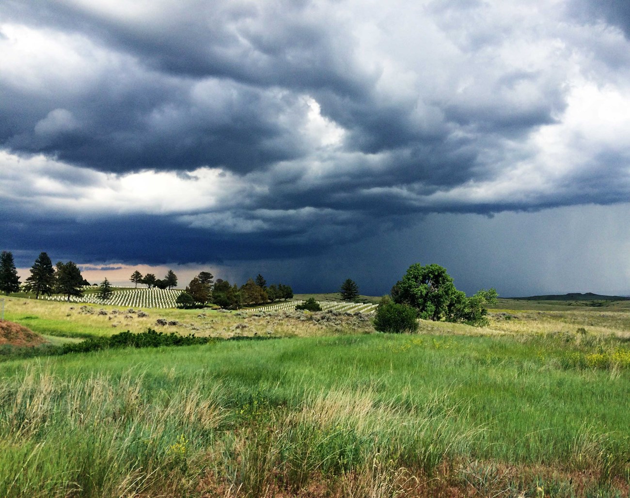 libi image storm dark storm clouds over rolling hills with grass and a cemetery.