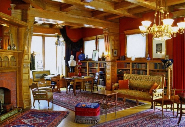 a home library with book cases and couches and chairs and a fireplace