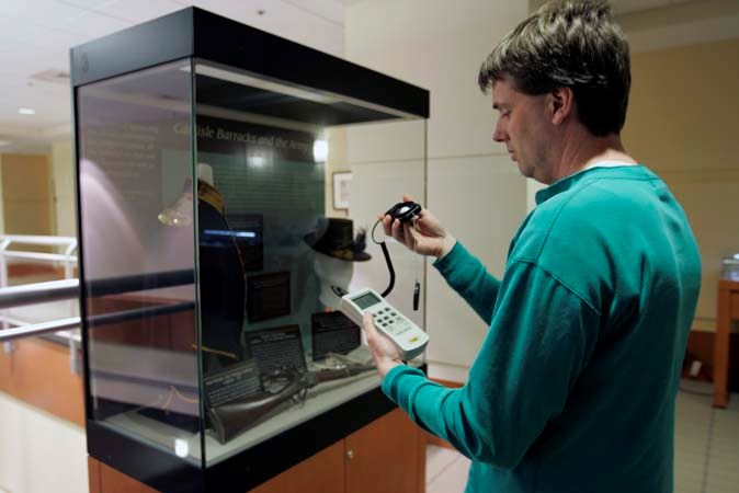 White man looking at a light monitoring instrument.