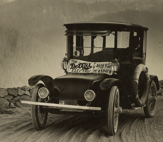 1920s car on a dirt road with a windshield sticker