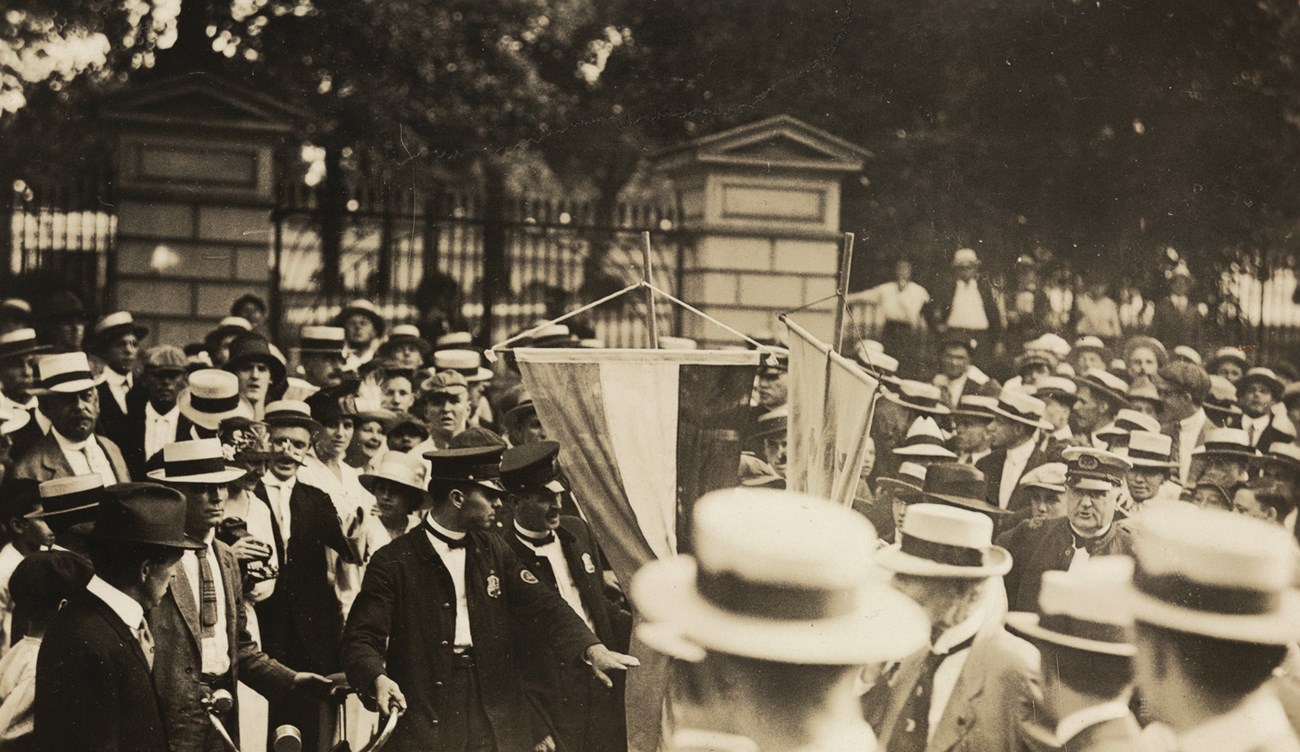Lavinia Dock and Edna Dixon arrested outside White House, 1917. Two police officers arrest an unseen person in the middle of a large crowd of men