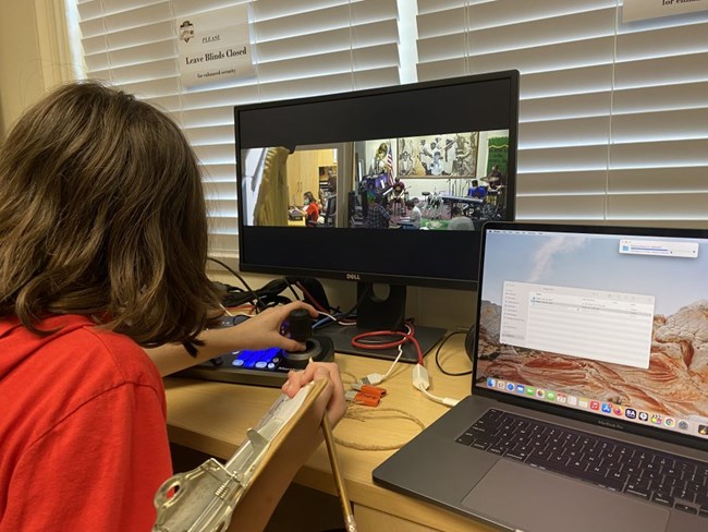 manuel project 2 student in front of two computer monitors, working the mounted camera controller while other students are in front of the camera