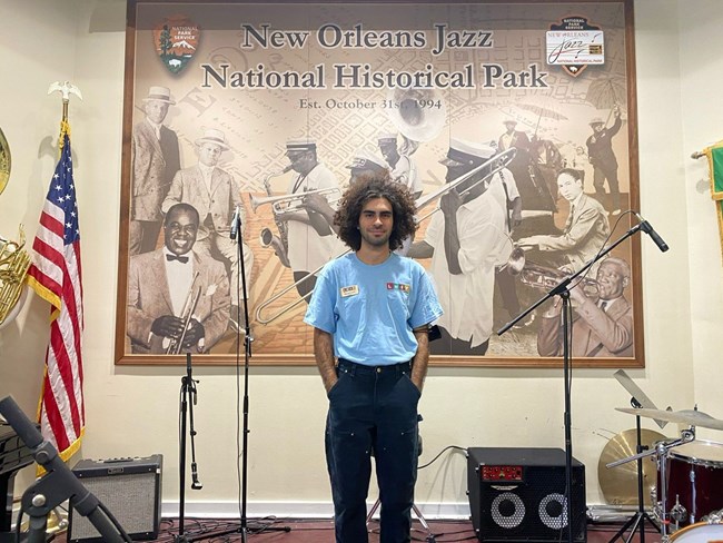 man with latino heritage internship program's blue shirt posing in front of a stage