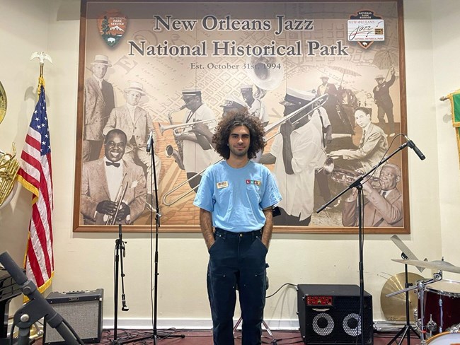 manuel santos man with latino heritage internship program's blue shirt posing in front of a stage