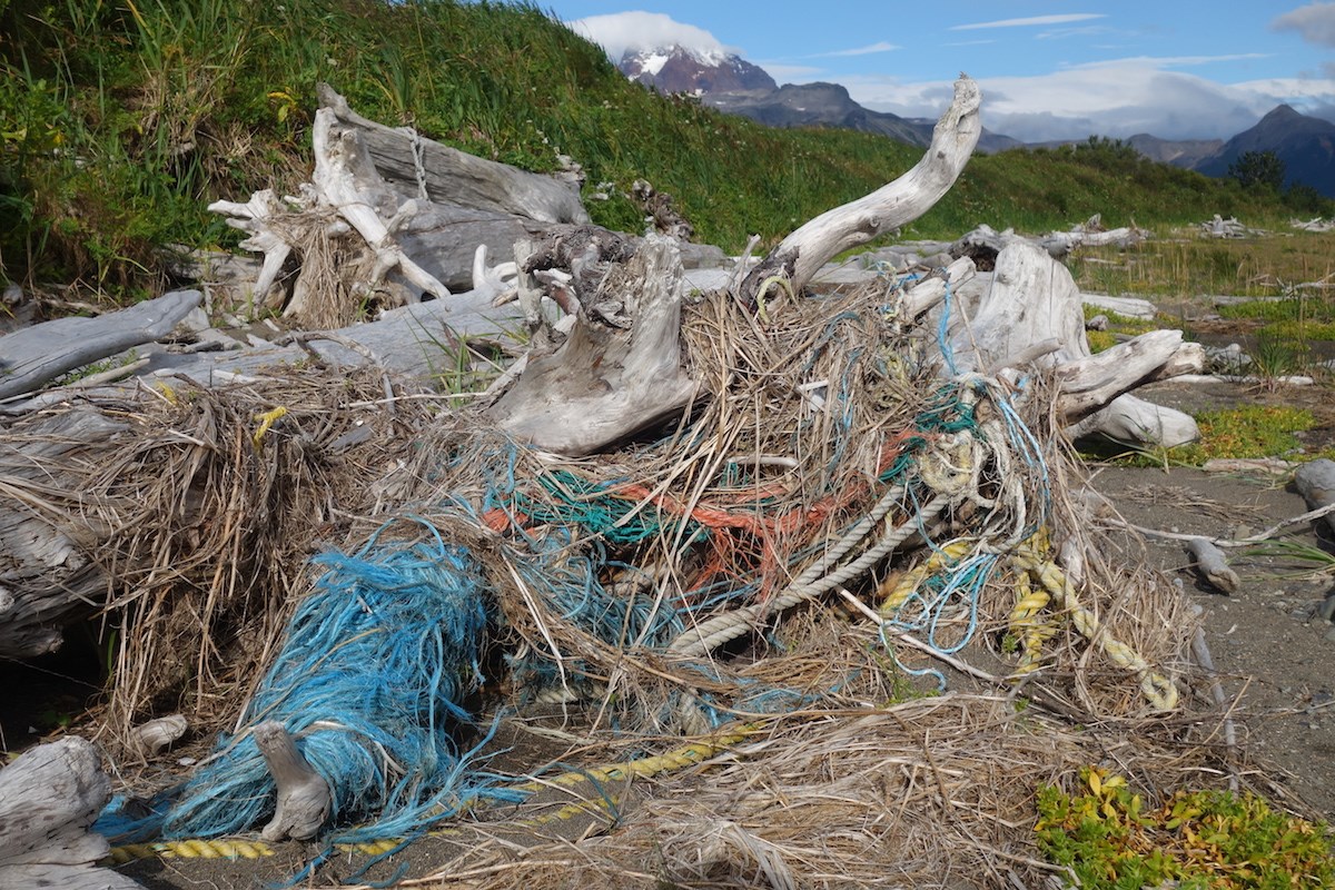 Marine debris discarded rope and netting washes up with driftwood along an Alaskan Coastline