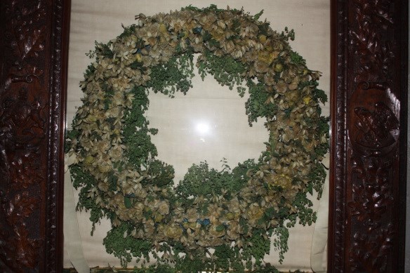 a large green wreath with little white flowers is encased in a wooden frame