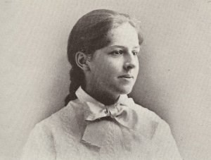 mollie-as-a-teenager a teenage girl who is wearing a dress and also her brown hair is in a braid behind her