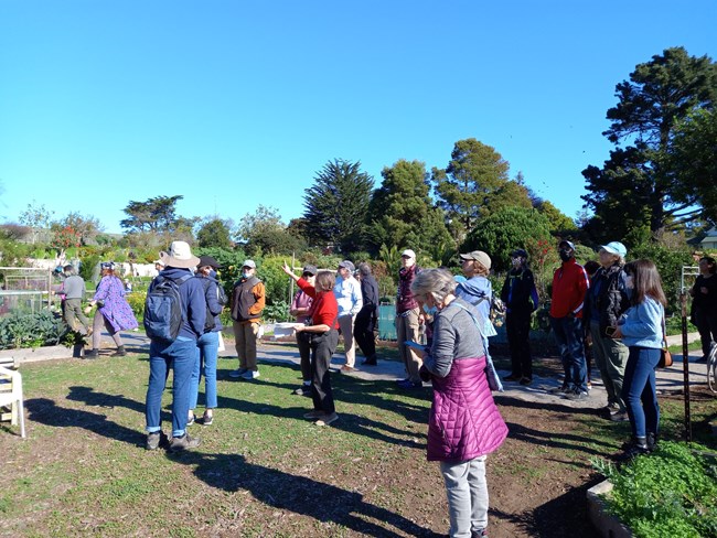 a group of people gather in a garden to learn about monarchs