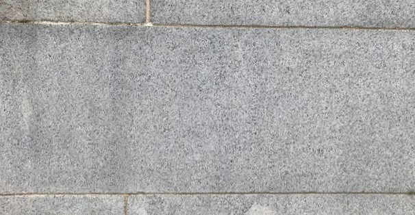 Close-up image of a granite block that is a part of a monument. Thin lines of mortar outline the block.