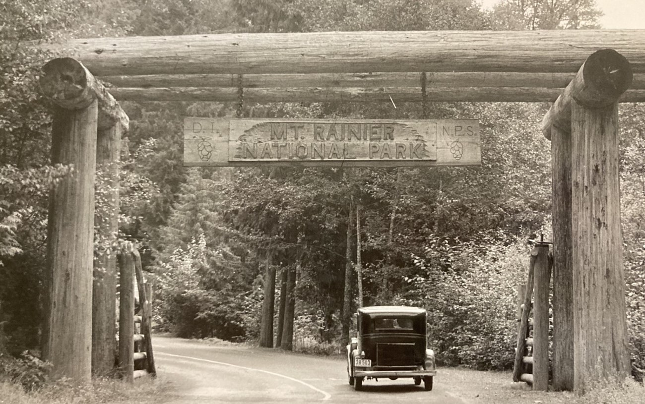 Large wooden entrance gate in front of a wooded area