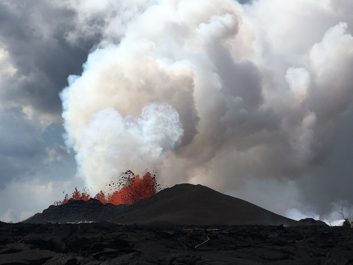 photo of erupting lava shooting up in a sky clouded with steam