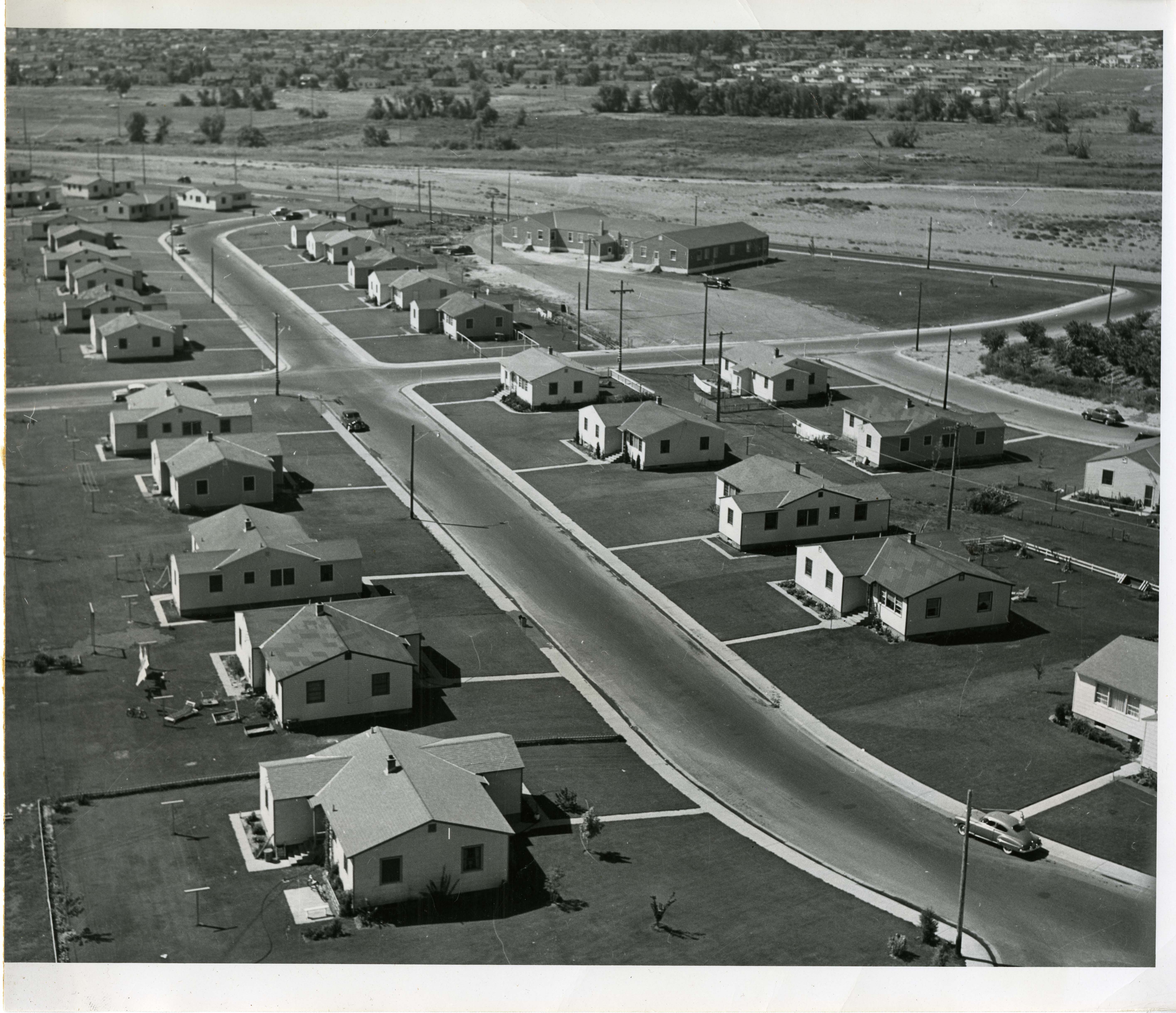 Historic photo of new neighborhood, about 13 homes on each side of the street, sidewalks and lawns.