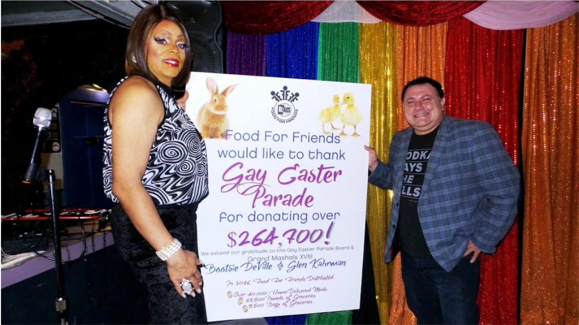 Two people posing with a Gay Easter Parade poster.