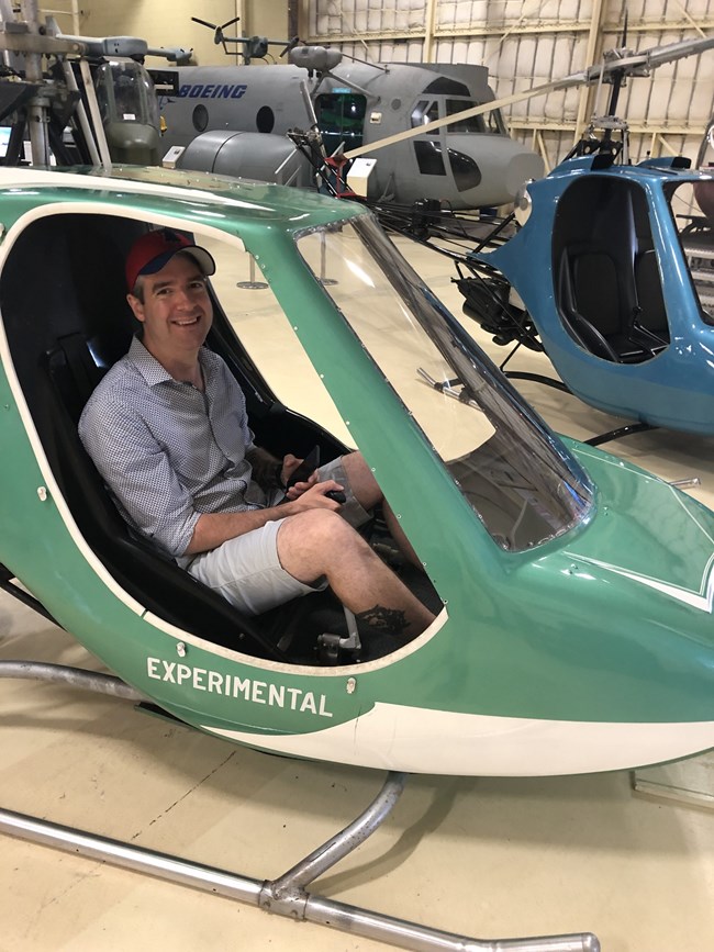 A visitor sits inside an experimental green and white Scorpion helicopter on display inside the main hangar.