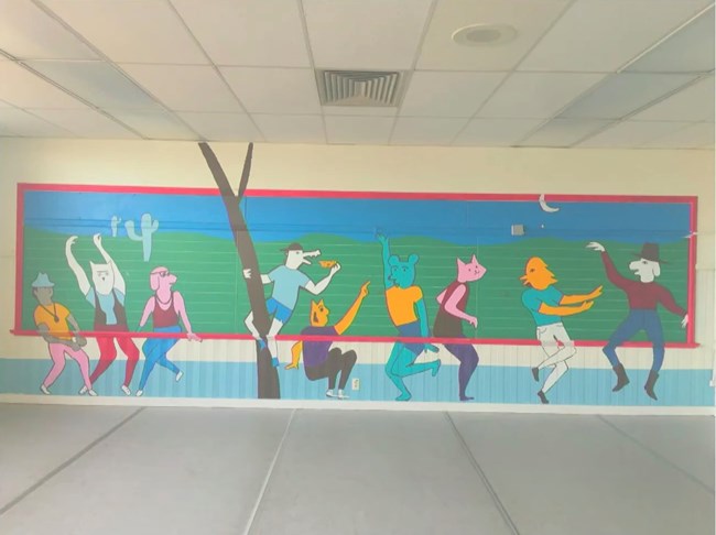 Green chalk board painted over with dancing animals.