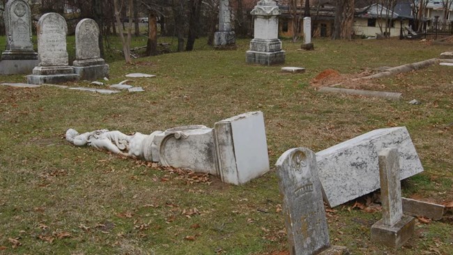 A statue figure on a pedestal has fallen from its base.