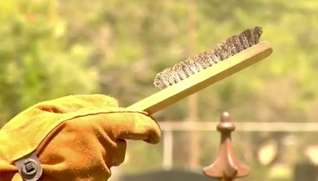 Use a handheld wire brush to clean the fence, not power tools.