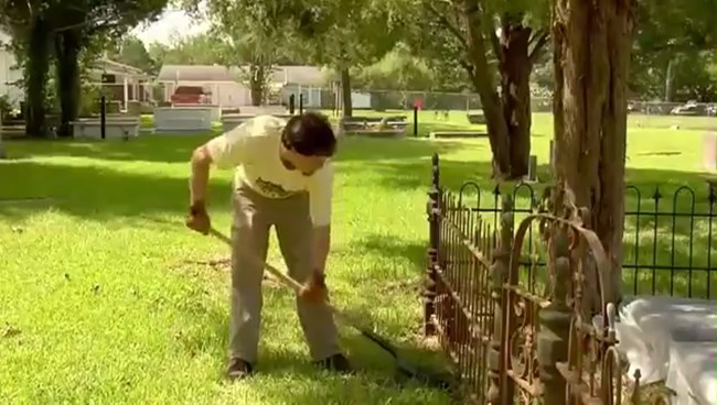 Jason Church carefully clears under the fence with a shovel.