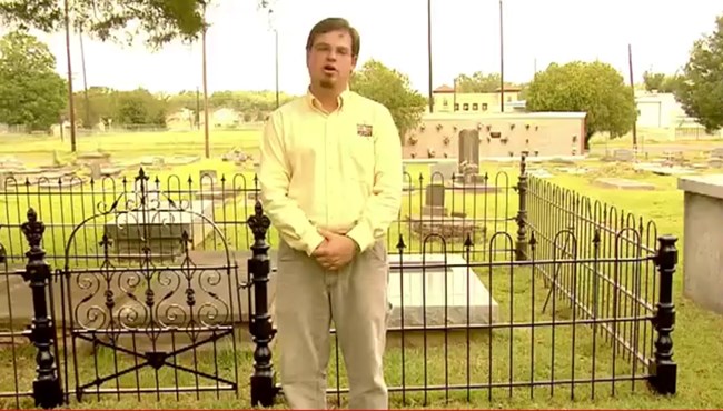 Jason Church stands in front of a repaired cemetery iron fence.