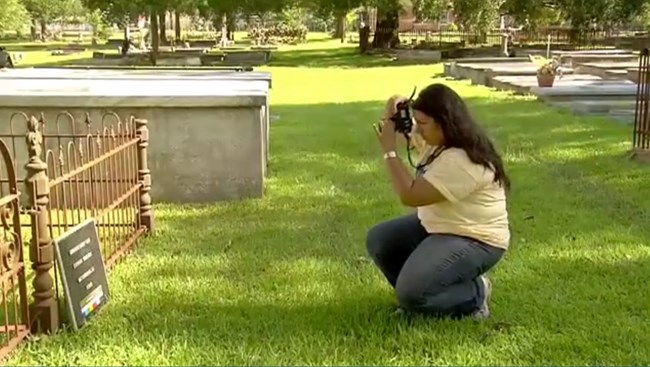 Bianca Garcia photographs a wrought iron fence before repairs.