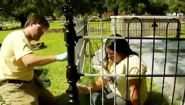 When choosing paint you will want an oil based paint designed for use with metal. Two coats are preferable to get a good solid surface coating. Jason Church and Bianca Garcia hand-paint the repaired iron fence.