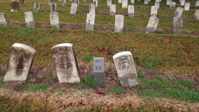 Uneven rows of headstones tilted or sunken, soldiers from the War of 1812 and other wars.