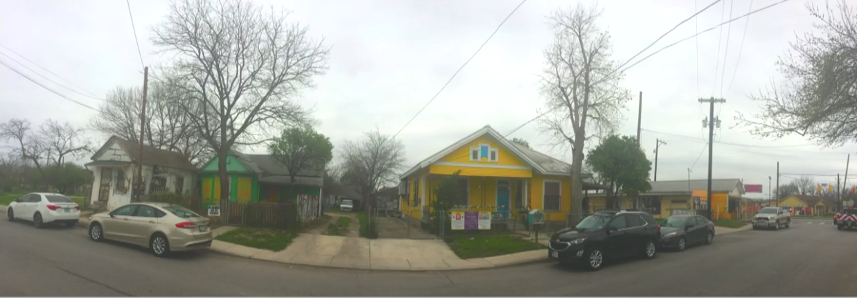 A street view of a neighborhood of small, colorful houses.