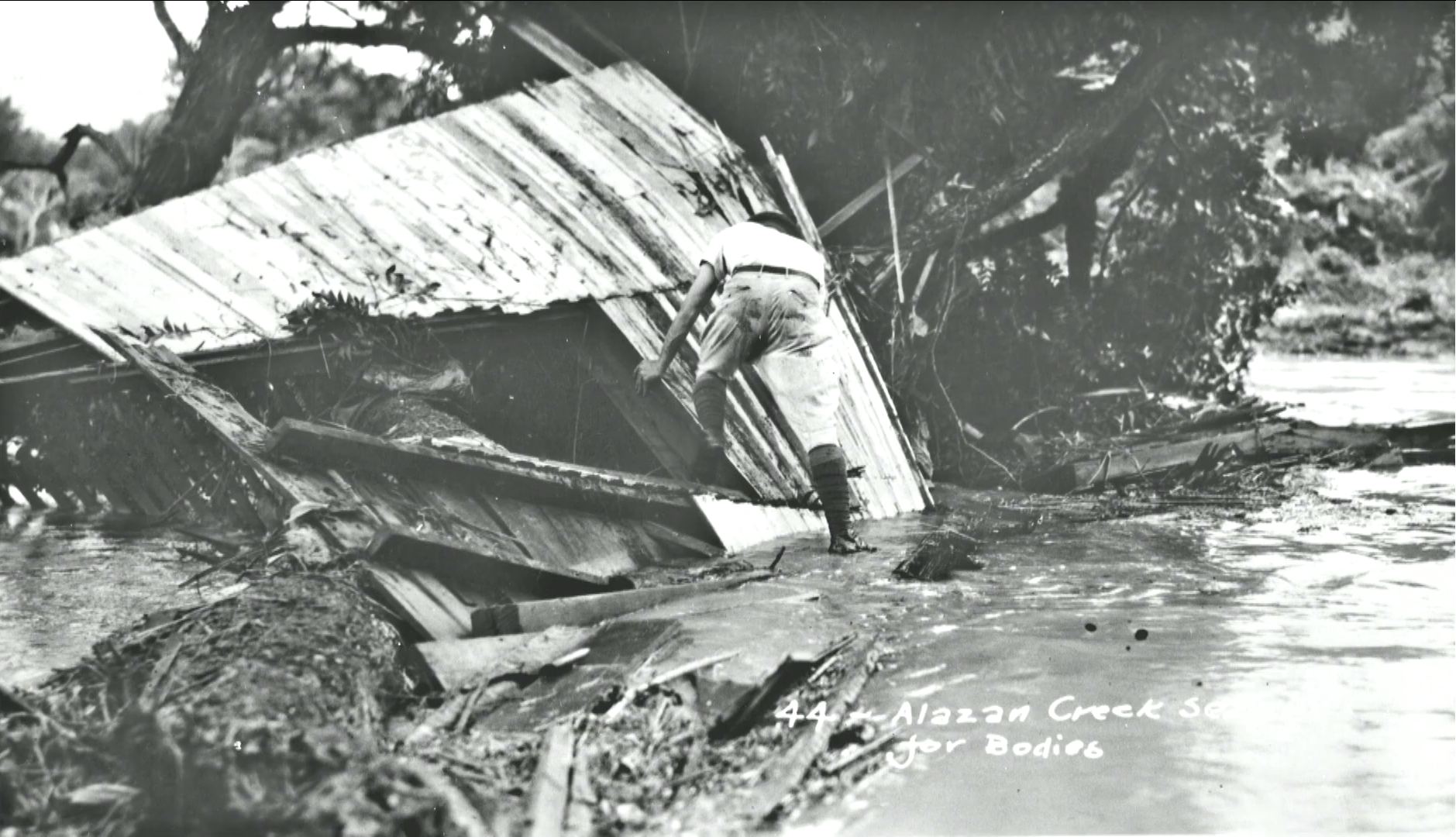 A man searches for bodies in the debris of homes along Alazan Creek.