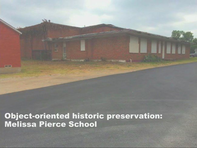 Melissa Pierce School: Object-oriented historic preservation. Red brick school and gymnasium, boarded up, overgrown with vegetation and neglected.