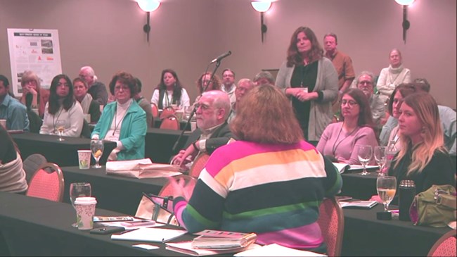 Audience members ask questions about the project. Photo of a full room of attendees asking and answering session questions.