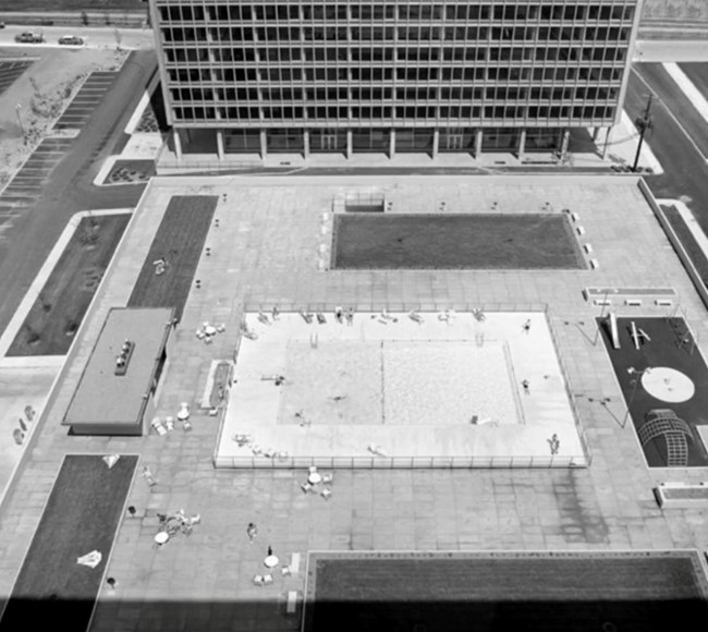 Two towers parallel with a pool and rec area central to the plaza and a parking garage between.
