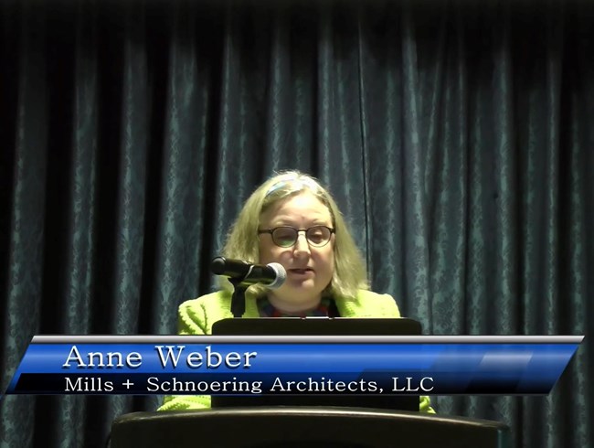 Anne Weber, Mills + Schnoering Architects Anne Weber standing at a lectern, presenting.